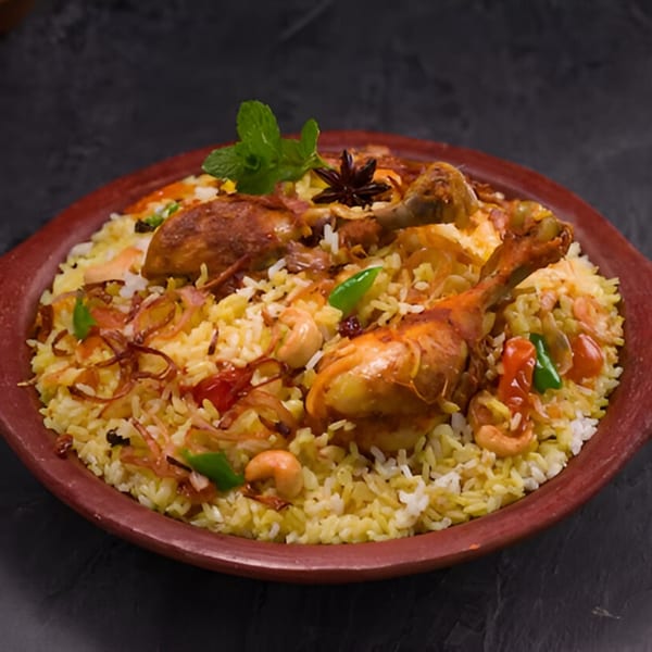 Saffron Restaurant's chicken biryani, garnished with mint, star anise, cashews, and fried onions.